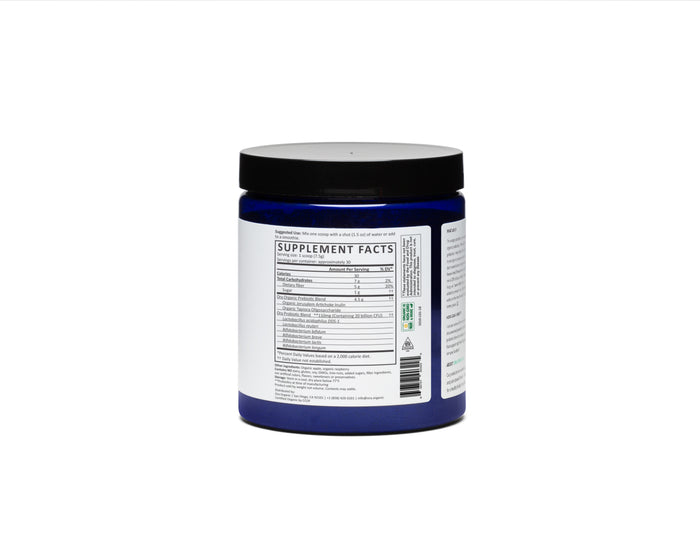 A blue jar featuring a black lid displays the nutritional label of Ora Organics Organic Probiotics with Prebiotics Powders. Photographed on a white background, it highlights the Supplement Facts chart, showcasing benefits for digestive health through its organic blend.