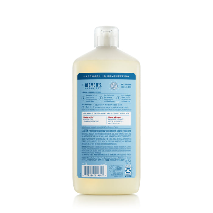 Back view of a Mrs. Meyers Ultra Concentrated Liquid Laundry bottle. The label is blue with white text detailing ingredients, usage instructions, and safety information. Infused with a garden-inspired scent, it features a recycling symbol at the bottom.
