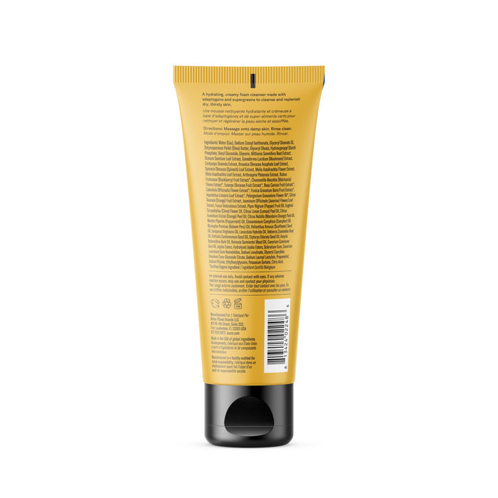 A yellow Acure Ultra Hydrating Green Juice Cleanser tube with a black cap is shown from the back, displaying densely packed text about ingredients, symbols, and a barcode.