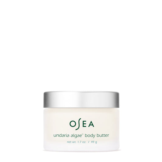 A small, minimalistic white jar with a silver lid is labeled OSEA Undaria Algae™ Body Butter. It contains 1.7 oz (49 g) of moisturizing product, featuring green text on a translucent background.