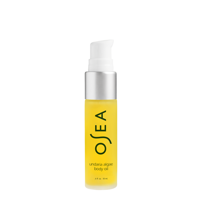 A transparent cylindrical bottle of OSEAs Undaria Algae Body Oil, featuring a pump dispenser, reveals its yellow seaweed-infused contents. The black label text enhances the organic botanical essence theme.