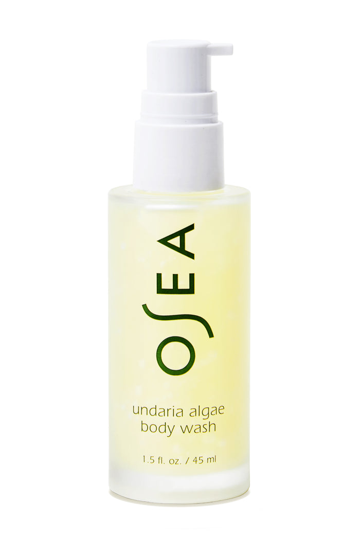 The 1.5 fl. oz. travel-sized bottle of OSEA Undaria Algae™ Body Wash, featuring a clear design with a white pump, displays OSEA and product details in green text. It highlights its pH-balanced formula and signature Undaria Algae Body Oil scent.