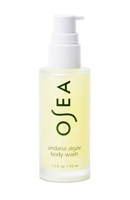 The 1.5 fl. oz. travel-sized bottle of OSEA Undaria Algae™ Body Wash, featuring a clear design with a white pump, displays OSEA and product details in green text. It highlights its pH-balanced formula and signature Undaria Algae Body Oil scent.