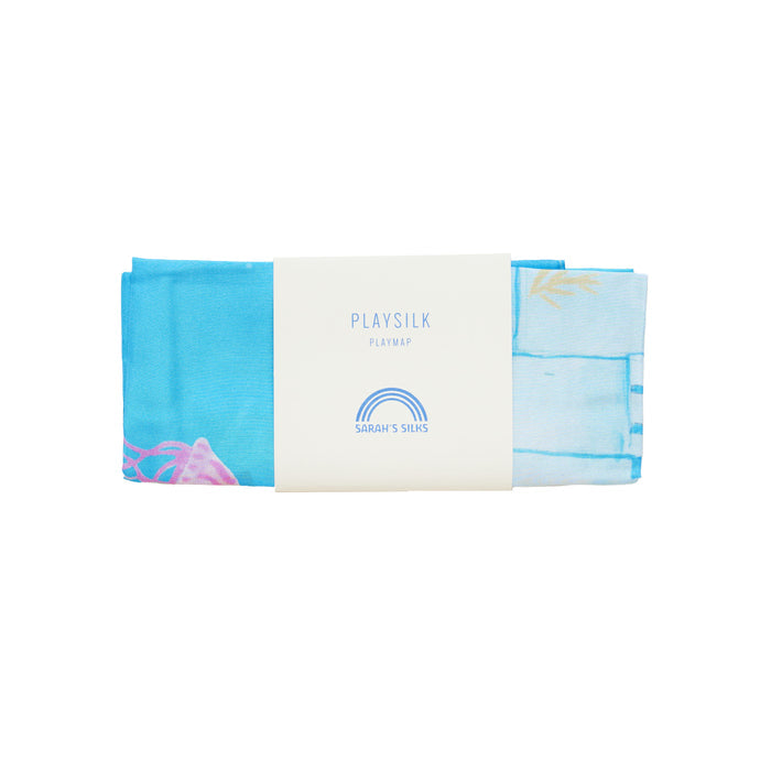 A folded blue playmat named Under the Sea Play Map by Sarahs Silks features a rainbow graphic and is made with non-toxic dyes for safe play. Its perfect for inspiring endless imaginative adventures.