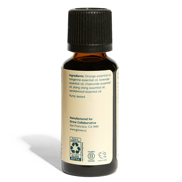 The Grove Co. Unwind Essential Oil Blend - Orange & Chamomile is a small amber glass bottle with a black cap, featuring organic essential oils of orange, tangerine, lavender, chamomile, ylang ylang, and sandalwood. Its purity-tested for aromatherapy; eco-certifications included.