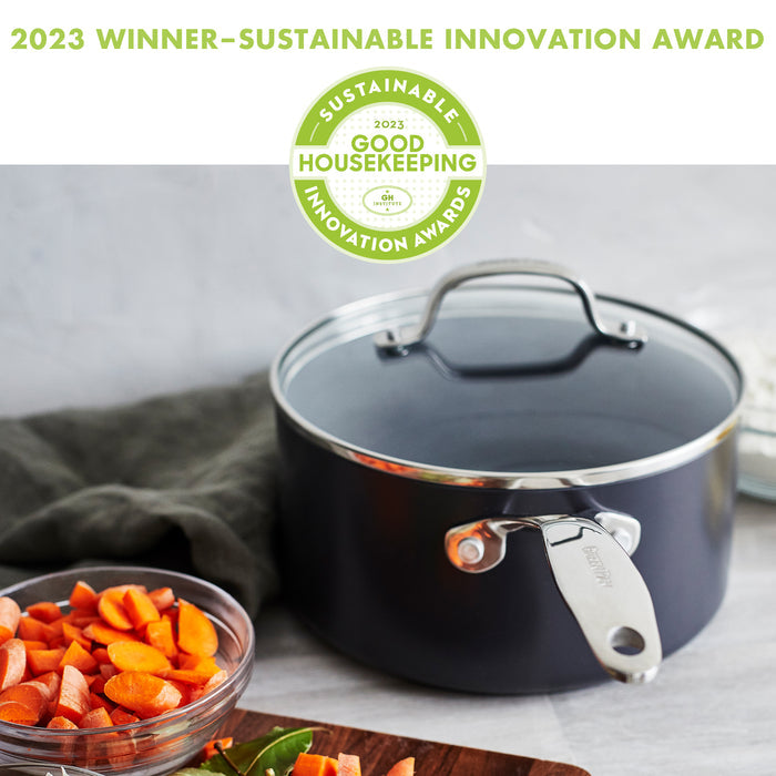 A black cooking pot with a lid sits on a kitchen counter. Next to it is a bowl filled with chopped carrots. Above the pot, text reads "2023 Winner - Sustainable Innovation Award." The Good Housekeeping Sustainable Innovation Award logo is also visible.