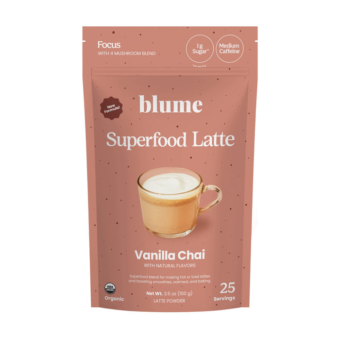 A pink packet of blumes Vanilla Chai Blend features a latte image and labels for organic, 25 servings, no sugar, medium caffeine, with natural flavors. It weighs 3.53 oz (100g) and combines creamy vanilla with aromatic spices in the Vanilla Chai flavor.