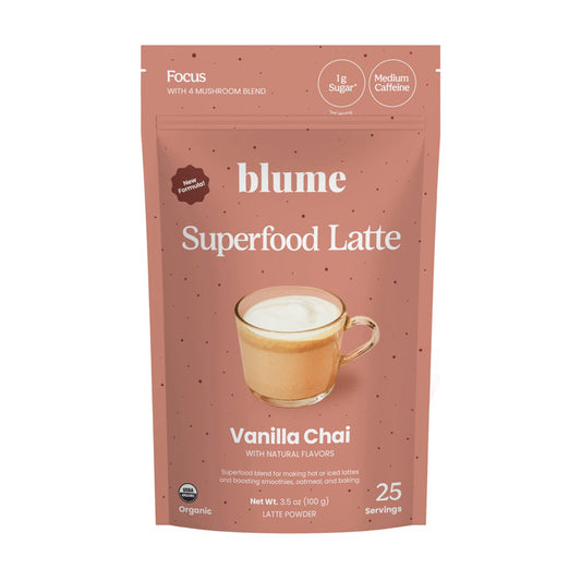 A pink packet of blumes Vanilla Chai Blend features a latte image and labels for organic, 25 servings, no sugar, medium caffeine, with natural flavors. It weighs 3.53 oz (100g) and combines creamy vanilla with aromatic spices in the Vanilla Chai flavor.