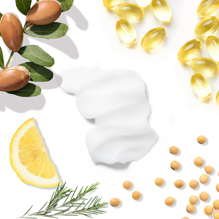 Flat lay on white: argan oil, nuts, leaves, gel capsules of Vegan Collagen & Biotin Conditioner by Tree To Tub, a cream smear, lemon slice, rosemary sprigs, and soybeans.