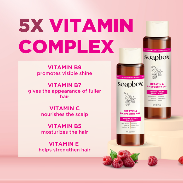 Image of two Soapbox bottles labeled Vegan Keratin & Raspberry Seed Oil Smoothing Shampoo. Text showcases a 5x Vitamin Complex: B9 for shine, B7 for fullness, C to nourish the scalp, B5 to moisturize, and E for strength. Color-safe formula with raspberries at bottom.