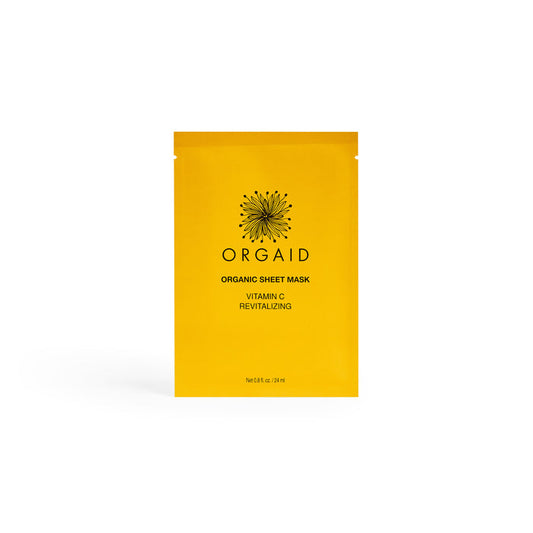 A bright yellow packet labeled ORGAID Vitamin C & Revitalizing Organic Sheet Mask with a sunburst design highlights Ecoderma fabric technology, containing 24ml (0.8 fl. oz.) of the organic face mask against a white backdrop.