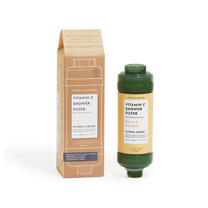 A green Vitamin C shower filter with vegan probiotics and its matching cardboard box stand upright, labeled Detox & Energize, Citrus Crush by the brand VOESH New York.