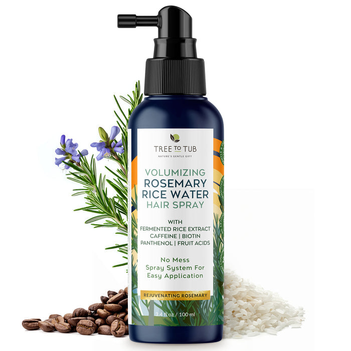 A dark blue bottle of Tree To Tub Volumizing Rosemary & Rice Water Hair Spray is equipped with a nozzle, promoting its hair health benefits. Surrounded by rosemary sprigs, coffee beans, and rice, its label emphasizes easy application and nourishing ingredients for fuller, thicker hair.