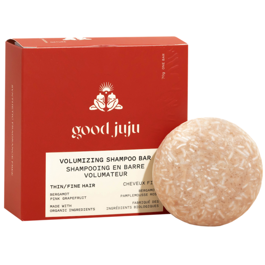 A round, beige Volumizing Shampoo Bar by Good Juju Body & Home sits before a red box. Made for oily/fine hair, it features bergamot and pink grapefruit to support natural hair growth.