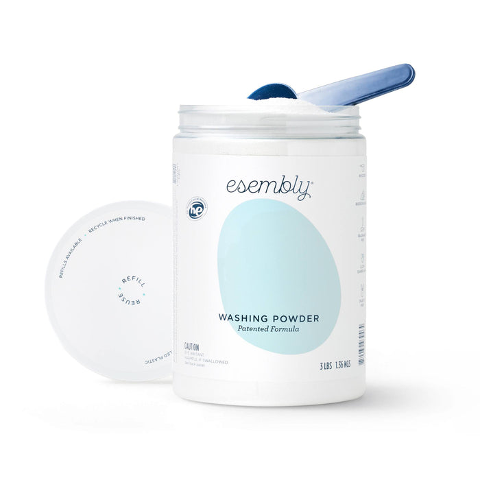 A 3 lb. white container of Esembly Babys Washing Powder, featuring a light blue oval design and label with a patented formula ideal for cloth diapers, reveals a blue scoop inside when opened. Eco-friendly and effective!.