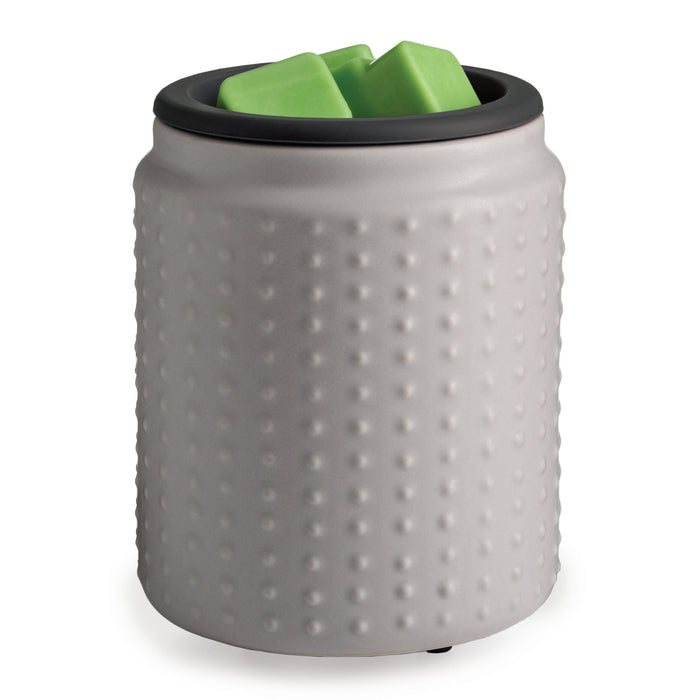 The Wax Warmer with Silicone Dish by Candle Warmers Etc. is gray with a dimpled surface, smooth black rim, and holds two green cube-shaped wax melts. Its cylindrical design adds charm to any room.