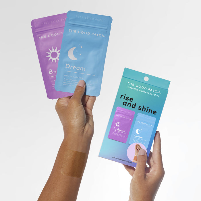 Two hands hold Wearable Wellness Patches by The Good Patch which include a B12 Awake packet and blue Dream patches with a moon and star. A matching Rise and Shine box aligns with the theme as a patch is applied on one hand.