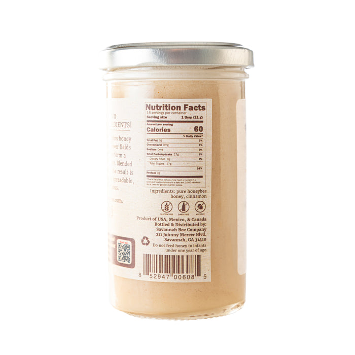 The Savannah Bee Companys Whipped Honey with Cinnamon comes in a glass jar with a silver lid, featuring nutrition facts and ingredients like organic Ceylon cinnamon and a QR code. This aromatic blend is made from honey sourced in the USA, Mexico, and Canada.