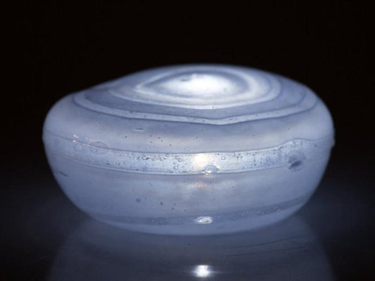 White frosted votive memorial stone glowing softly with an LED tealight inside.