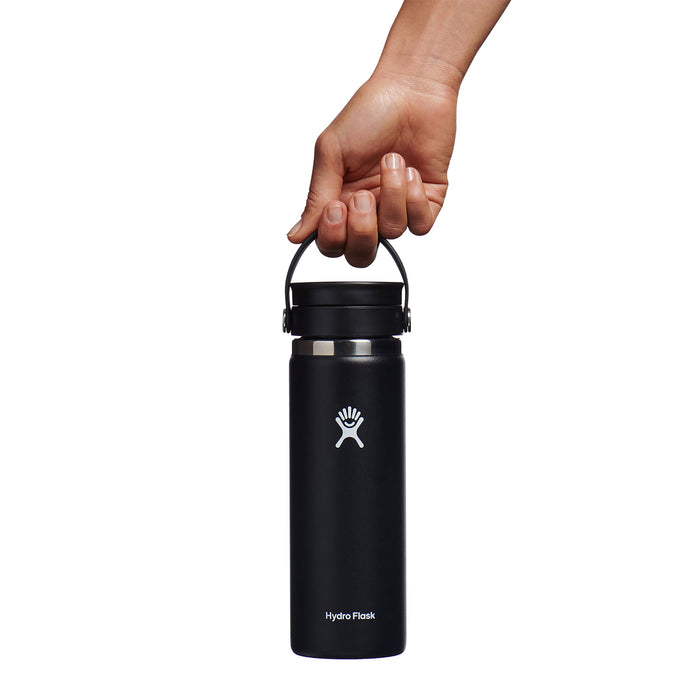 A hand holds a black 20 oz Hydro Flask Wide Mouth Bottle with a Flex Sip Lid™, featuring TempShield double-wall insulation, white logo and text. The leakproof design and sturdy lid handle are set against a plain white background.