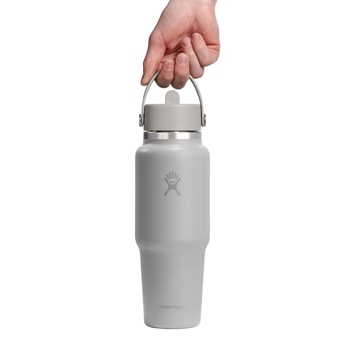A hand holds the sleek gray stainless steel 32 oz Hydro Flask Wide Mouth Travel Bottle with Flex Straw Cap against a white background, showcasing its logo and brand reputation for maintaining drink temperatures.