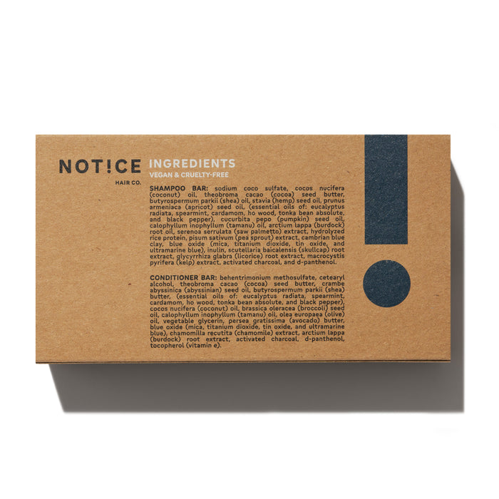 A brown rectangular box labeled NOT!CE Hair Co offers the Wingman Travel Set with vegan and cruelty-free shampoo and conditioner bars enriched with essential oils. Natural ingredients promote sustainable self-care, and a large exclamation mark emphasizes its eco-friendly commitment.