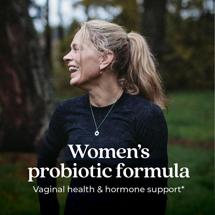 A woman laughing outdoors, wearing a dark top with a necklace. The text on the image reads, "Women's probiotic formula - Vaginal health &amp; hormone support." The background shows trees and grass.