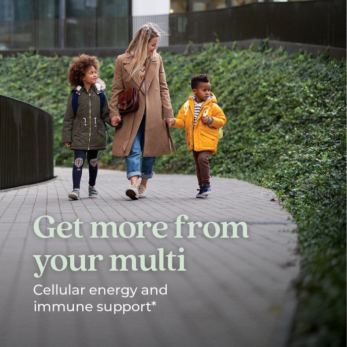 A woman with two kids strolls outdoors in coats and backpacks amid greenery. Text: Get more from New Chapter Women’s Multivitamin Gummies—nutrient packed, less sugar, berry citrus flavor for cellular energy & immune support.*.