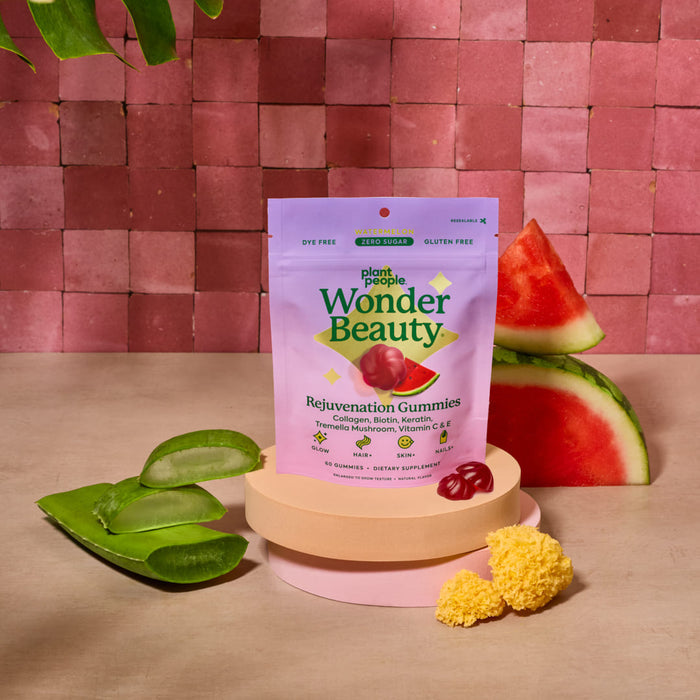 A bag of Plant People WonderBeauty Gummies is displayed with aloe vera, watermelon, and a sponge on pink tiles, showcasing collagen gummies for hair, skin, and nails with vitamins and natural ingredients.