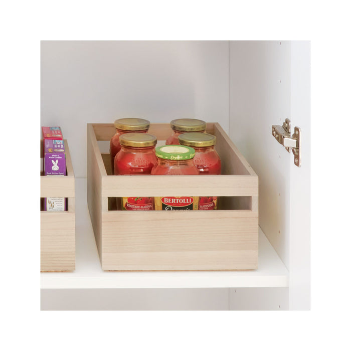 An iDesign Wood Handled Bin, made from renewable materials, holds glass jars of tomato sauce on a white shelf. Next to it sits another bin with boxed items. The open door reveals a metal hinge, highlighting stylish and eco-friendly organization.