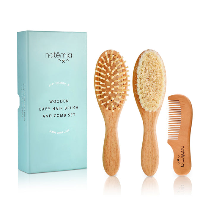 A Natemia Wooden Baby Hair Brush & Comb Set is shown, including a soft bristle brush, a gentle fuzz brush, and a comb. They are placed next to a light blue box labeled Natemia: Wooden Baby Hair Brush & Comb Set.