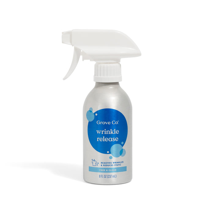 A silver Grove Co. Wrinkle Release Starter Kit features an 8 fl oz (237 ml) eco-friendly bottle with blue label, white reusable sprayer, and text stating it removes wrinkles and reduces static. Includes Reusable Sprayer Attachment.
