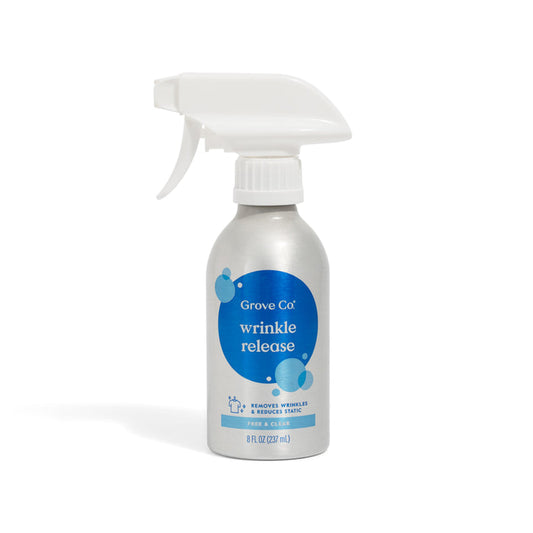 A silver Grove Co. Wrinkle Release Starter Kit features an 8 fl oz (237 ml) eco-friendly bottle with blue label, white reusable sprayer, and text stating it removes wrinkles and reduces static. Includes Reusable Sprayer Attachment.