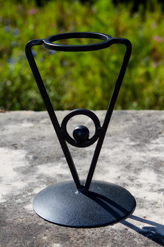 Black wrought iron triangle stand with circular top ring holds a globe-like orb outdoors