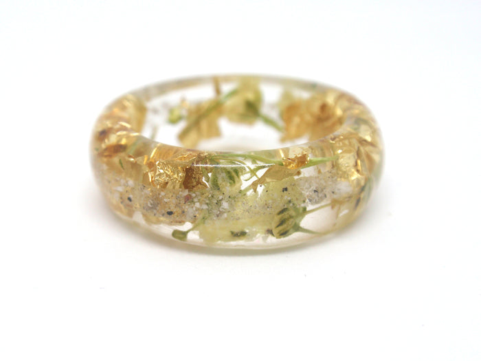 Clear resin ring embedded with dried yellow flowers and gold flakes infused with cremains.