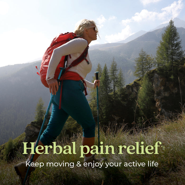 A woman hiking on a grassy mountain trail with trekking poles, wearing a red backpack and sunglasses. The sky is partly cloudy. Text on the image reads: "Herbal pain relief. Keep moving &amp; enjoy your active life.